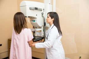 health-care-practitioner-helping-a-woman-use-a-mammogram-machine